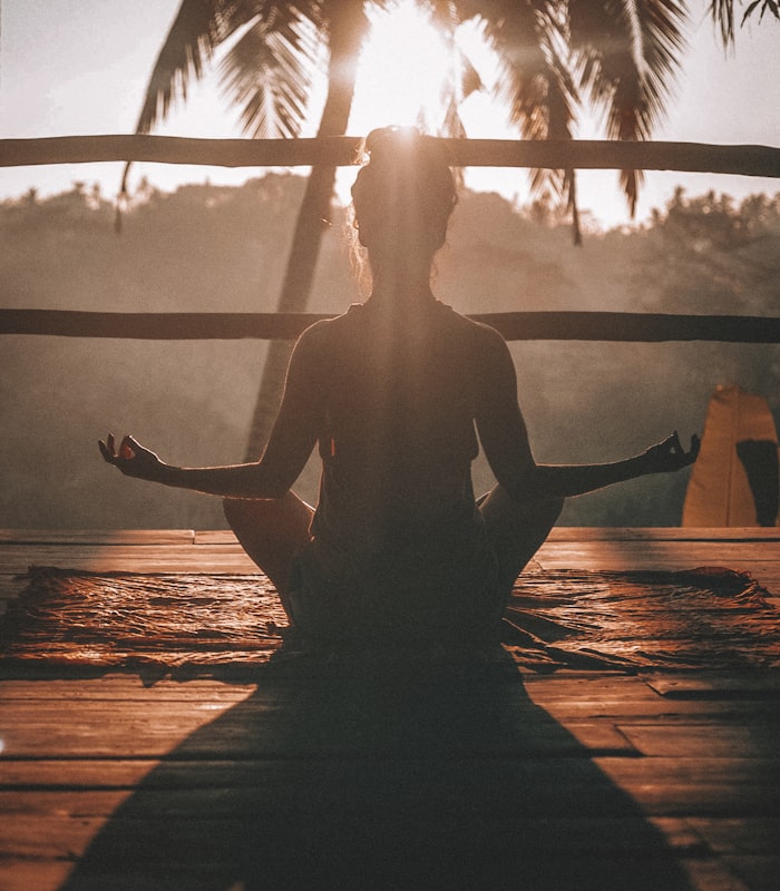 Kobieta medytująca o wschodzie słońca w otoczeniu natury - holistyczny wellness Blisko Natury